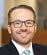 A man wearing a blue tie and a black suit. Description generated by AI