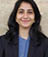 A woman wearing a blue shirt and black jacket. Description generated by AI