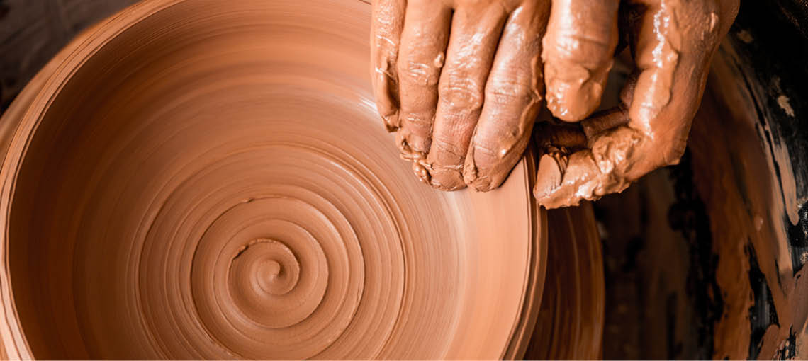 A person is shaping a clay pot. Description generated by AI