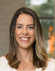 A woman with long brown hair and a white shirt. Description generated by AI