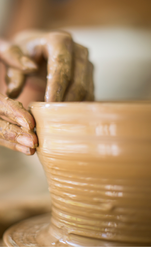 A person is shaping a clay pot. Description generated by AI