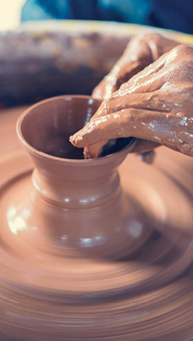 A person is making a pot with brown clay. Description generated by AI