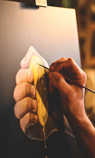 A person is painting a picture of a hand holding a lemon. Description generated by AI