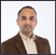 A man wearing a brown jacket and a white shirt. Description generated by AI