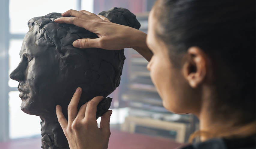 A woman is touching a clay head. Description generated by AI